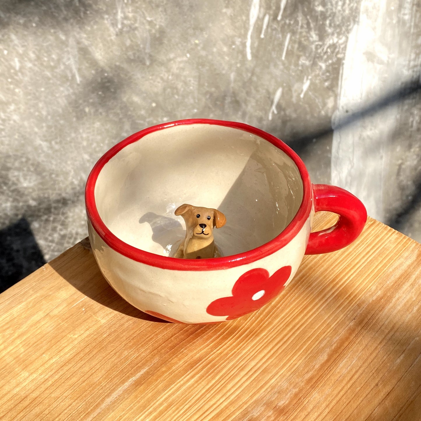 Handmade ceramic mug with red handle and flower pattern, featuring a 3D dog figure inside the cup