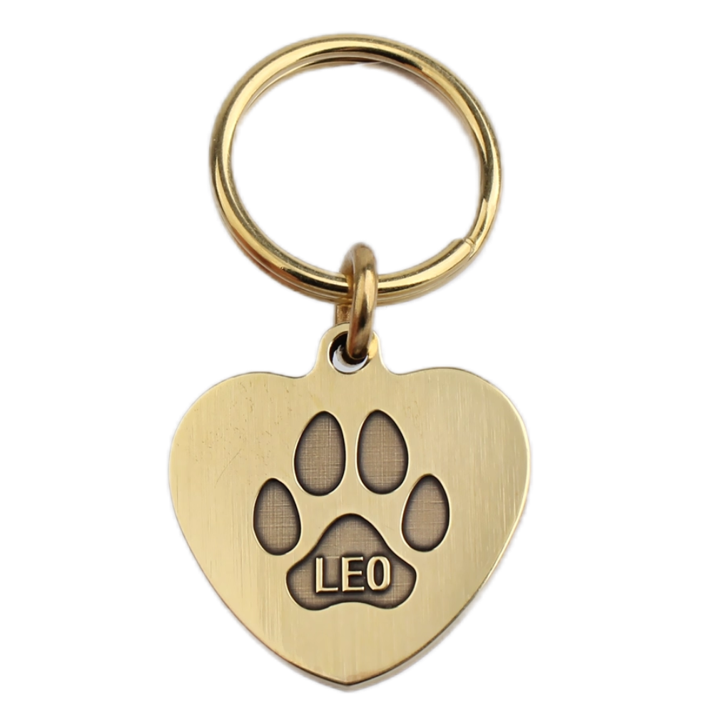 Heart-shaped brass pet tag with engraved paw print and name Leo.