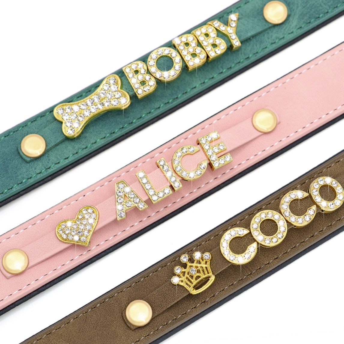 Close-up of green, pink, and brown pet collars with rhinestone letters and gold charms.