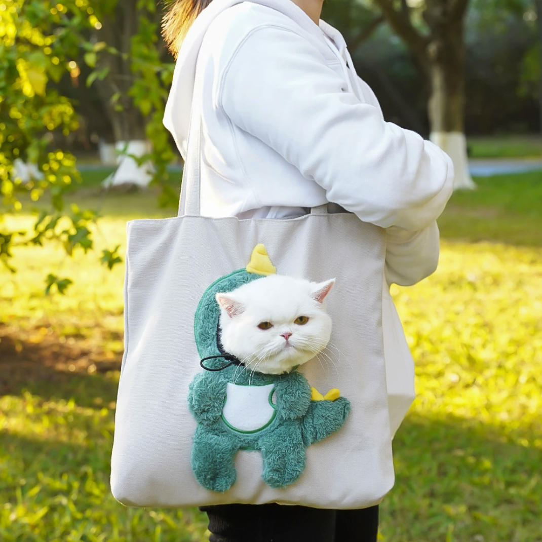 Grey tote with green dinosaur costume and cat’s head showing