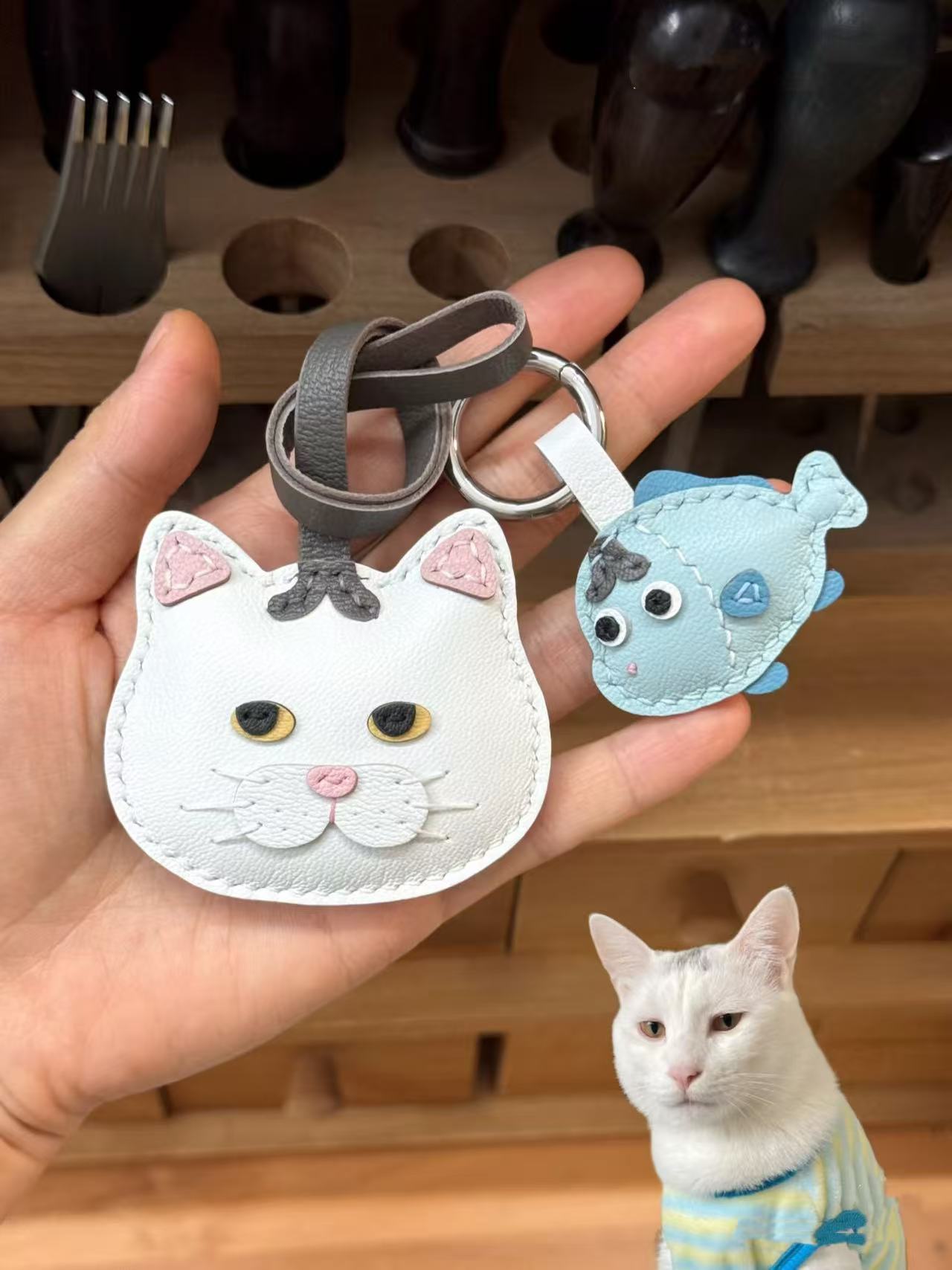 Handmade cartoon-style cat leather charm in white with blue fish accessory, crafted from goatskin leather, ersonalized from pet image