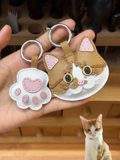 Custom cartoon cat leather charm in white and brown, with matching pink paw charm, made from goatskin leather, based on real pet photo