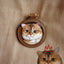 Realistic leather pet portrait charm of a British Shorthair cat in a stitched round brown frame with gold rivet, based on real photo