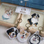 Three embroidered dog keychains with happy expressions, placed beside custom dog artwork and denim shirt embroidery.