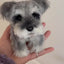 Twist yarn stick of a miniature schnauzer with gray and white fur, shown on palm