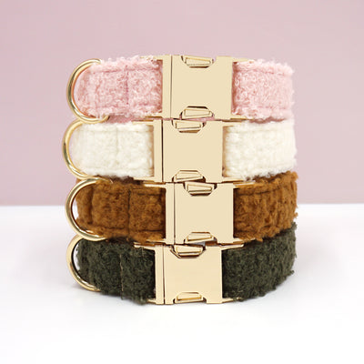 Set of teddy fleece pet collars in pink, white, brown, and dark green with gold buckles stacked together.