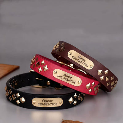 Three studded leather dog collars in red, brown, and black with engraved nameplates stacked together.